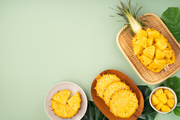 Fresh pineapple chunks served in a pineapple bowl on green table background.