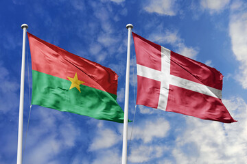 A Burkina Faso and Denmark flag, a metaphor for European-African collaboration, wave together against a blue sky, symbolizing friendship and cultural exchange.