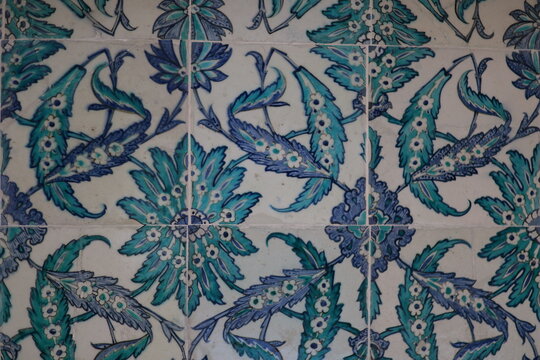 Ottoman ceramic tiles with vibrant floral patterns featuring large turquoise blossoms and stylized saz leaves on a cream background, rich in detail and symmetry.