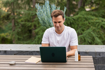 Man buying body products online using laptop on terrace