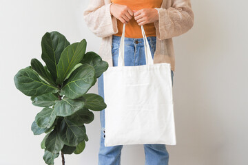 Woman holding canvas tote bag on white background. Reusable eco bag for shopping. Eco friendly concept. Mockup for design.