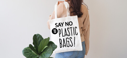 Woman holding canvas tote bag on white background. Say no to plastic bags. Reusable eco bag for shopping. Eco friendly concept. 