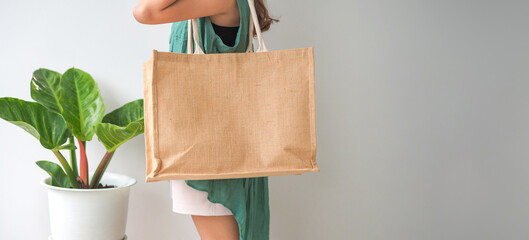Woman holding  jute bag or sack bag on white background. Reusable shopping bag. Natural material. Zero waste. Plastic free. Eco friendly concept.