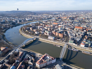 Naklejka premium Krakow, Poland: Aerial view of the historic Kazimierz district and the Father Bernatek’s Bridge over the Vistula river in Krakow on a sunny winter day in Poland.