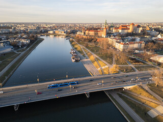 Krakow, Poland: Aerial view  of a tramway driving on a bridge over the Vistula river with the famous Wawel Royal Castle in the background on a sunny winter day in Poland.