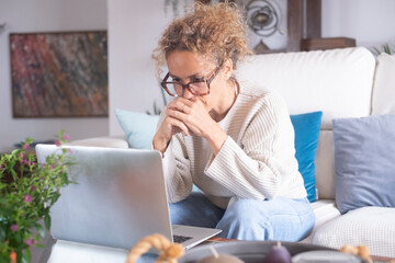 Middle-aged woman working from home on laptop. Mature female freelancer showing different facial...
