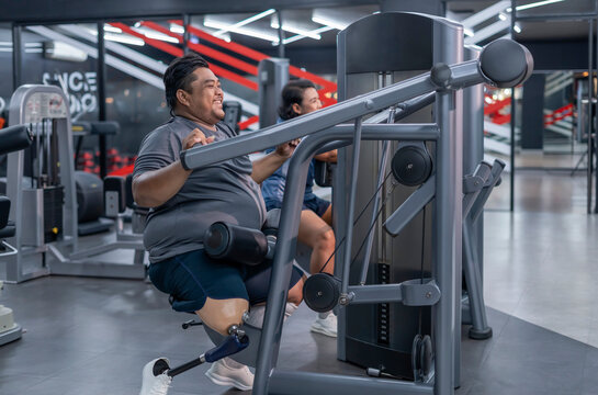 smiling obesity man,person with prosthetic leg doing sport training on fitness equipment,athlete,desire to lose weight,be strong,health and rehab