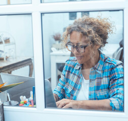 Mature woman working remotely from home using laptop computer. Middle-aged freelancer or remote...