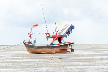 A boat is sitting on the beach with a flag on it