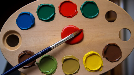 A wooden palette with multiple circular blobs of paint in various colors