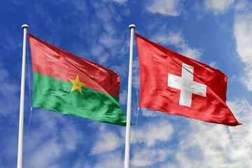 A Burkina Faso and Switzerland flag, a metaphor for European-African ties, wave together against a blue sky, symbolizing friendship and cultural exchange.