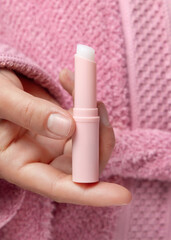 Woman in pink bathrobe holding in hand opened lip balm stick closeup, girly cosmetic mockup