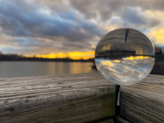 Lens Ball on Weathered Wood Capturing a Sunset Landscape