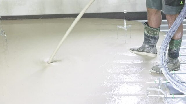 Construction worker pouring liquid cement for floor leveling