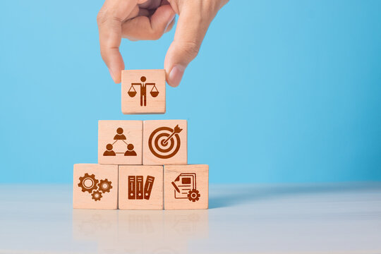 Wooden cube with ethics symbol held in hand. Represents corporate responsibility, integrity, and compliance in business practices.