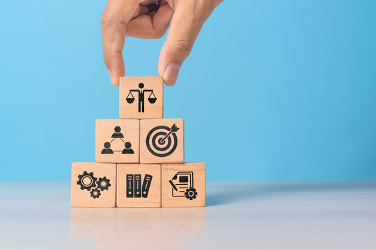 Hand holding wooden block with Ethical icons, business ethics and corporate compliance concept