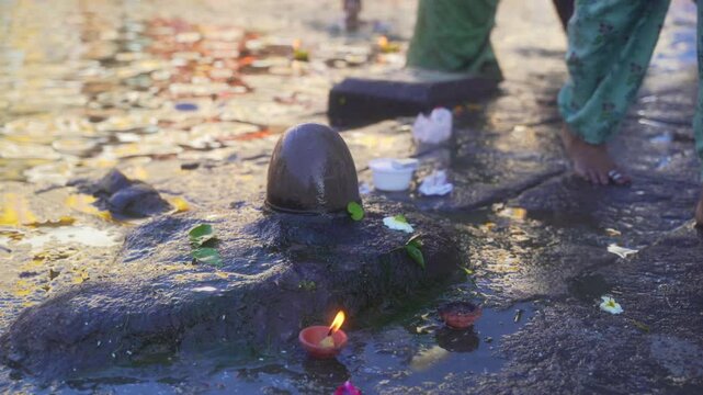 Woman devotee offering holy water of godavari river to Shiva Lingam at Ganga Ghat, Maha Kumbh 2027, Nashik, Maharashtra