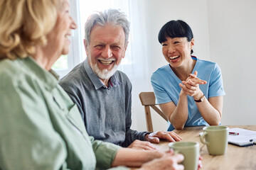 Doctor or nurse caregiver with senior couple at home or nursing home