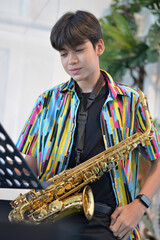 Teenager boy playing saxophone musician standing in the restaurant 