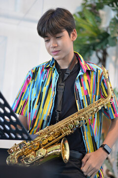 Teenager boy playing saxophone musician standing in the restaurant 