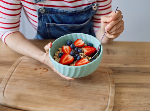 Portrait of a healthy young asian woman enjoying delicious fruit and cereal salad breakfast bowl at home
