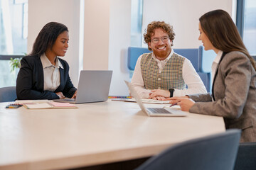 In a modern office, professionals collaborate and share ideas in meetings, using laptops for productivity