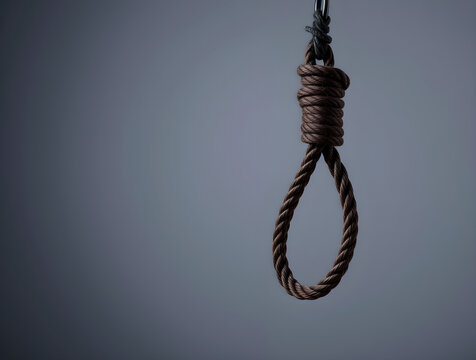 Rope noose hanging from metal on dark background symbolizing suicide