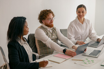 A diverse and enthusiastic team collaborates effectively and meets productively while using tablets...
