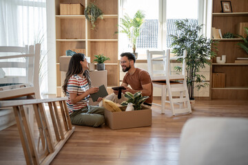 Happy couple unpacking boxes in new home after moving in