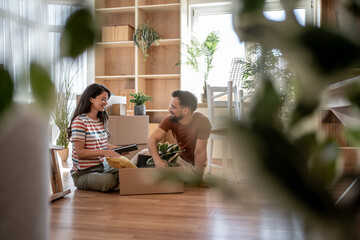 Young couple unpacking boxes in new home after moving in, starting new life together