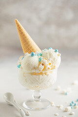 Vanilla ice cream balls with popcorn and pastry sprinkles in a cream bowl on a light background