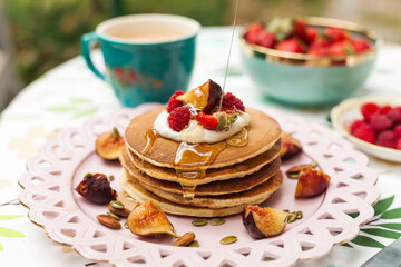 Fluffy pancakes with berries, whipped cream, and nuts. Served with warm milk tea for a sweet and cozy start to the day