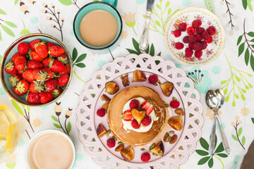 Fluffy pancakes with berries, whipped cream, and nuts. Served with warm milk tea for a sweet and cozy start to the day