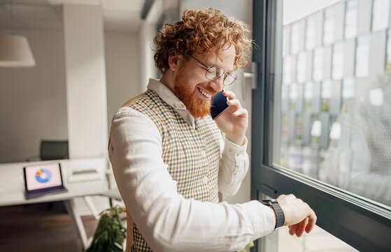 A focused business professional is on a call while checking a smartwatch in a stylish modern office