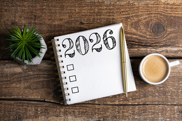 New year resolutions 2026 on desk. 2026 goals list with notebook, coffee cup, plant on wooden table. Resolutions, plan, goals, action, checklist, idea concept. New Year 2026 resolutions, copy space