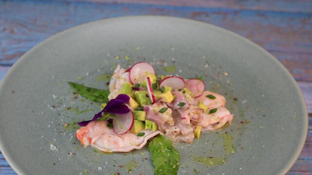 Delightful ceviche made with fresh dorade and shrimp, complemented by avocado and radish, garnished with an edible flower on a serene green plate.