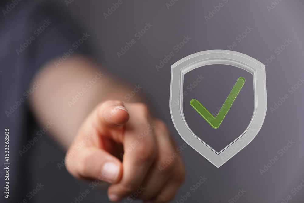 Aufkleber Stock photo of a hand pointing at a digital shield with a check mark, symbolizing data protection and security.