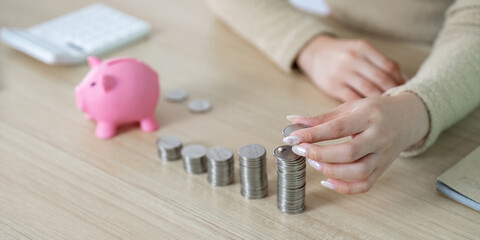 Coin Organization. Woman stacking coins next to a piggy bank at home.