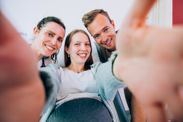 Happy pregnant woman taking selfie with doctor and husband