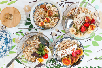 A set of cozy bowls of oatmeal topped with fresh fig, banana, strawberries, and black grapes. Healthy, beautiful, and satisfying family brunch 