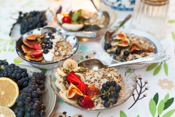 A set of cozy bowls of oatmeal topped with fresh fig, banana, strawberries, and black grapes. Healthy, beautiful, and satisfying family brunch 