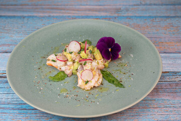 Delightful ceviche made with fresh dorade and shrimp, complemented by avocado and radish, garnished with an edible flower on a serene green plate.
