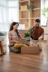 Happy couple unpacking plants and belongings in new home