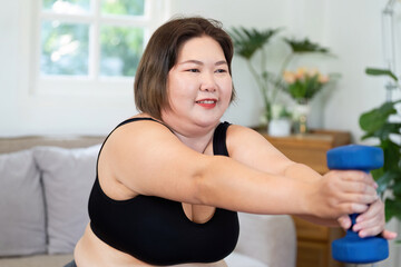 Inclusive Wellness. Plus-size woman exercising with dumbbell at home.