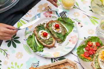 Rustic avocado toasts on oval bread served for a cozy family brunch with orange juice, croissants,...