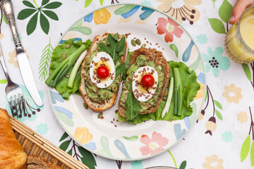Rustic avocado toasts on oval bread served for a cozy family brunch with orange juice, croissants,...