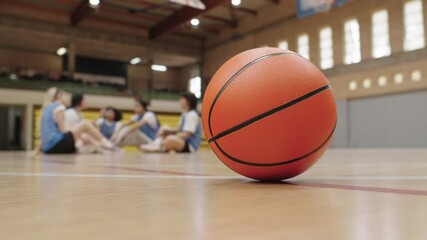 Basketball stands still as female players rest on court - Powered by Adobe
