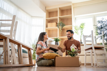 Happy couple unpacking boxes and furnishing new home together