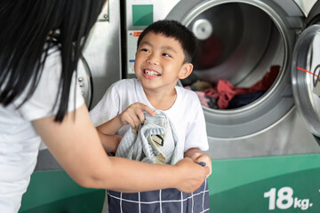 Cleaning and Family Bonding. Child helping mother with laundry at laundromat.