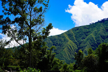 Panoramic view of green landscape with mountains, blue sky and white clouds from Selong Hill, Sembalun, Lombok, West Nusa Tenggara, Indonesia.